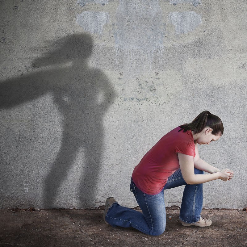 A woman prays while her shadow is a superhero.
